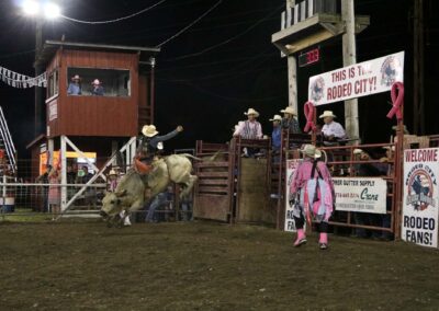 A cowboy rides a bucking bull at a rodeo