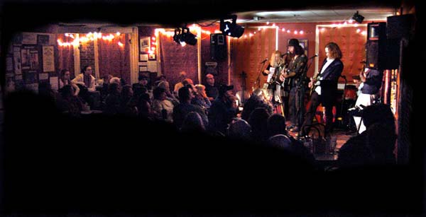 Musicians perform in a dark crowded cafe