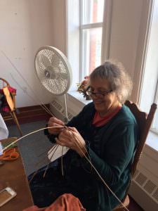 Bonnie Gale sits while working with a strip of willow