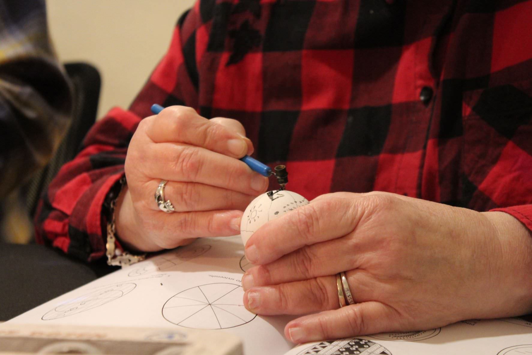 hands tracing a design on an egg