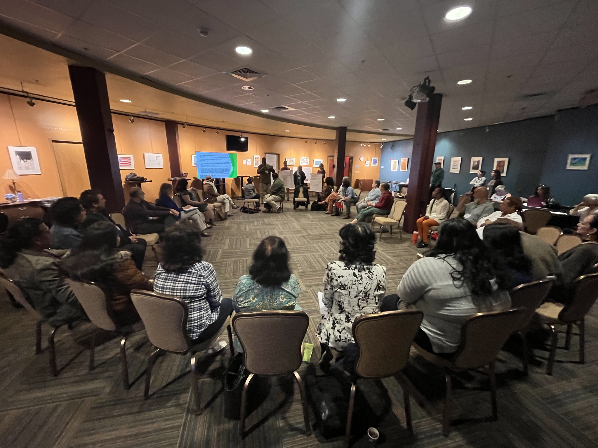 artists sitting in a large cirle watching a presentation