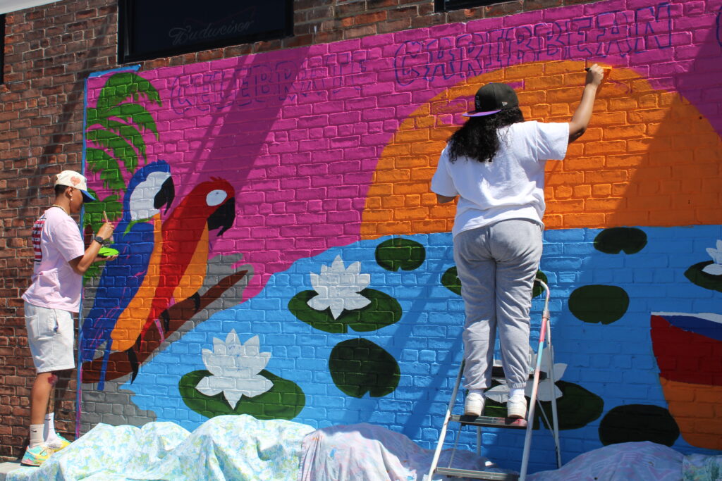 Two people paint a brightly colored mural