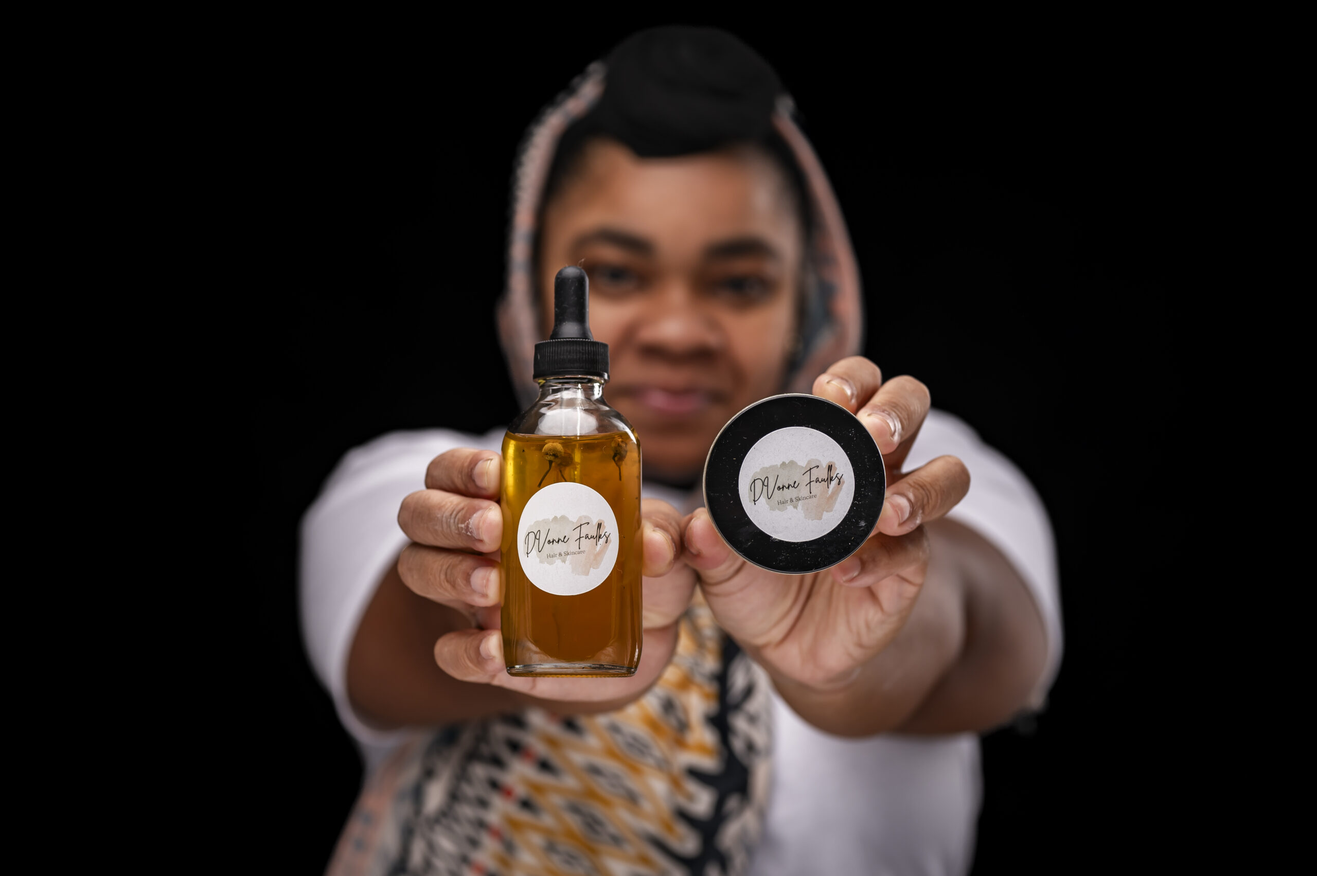 A photo of D'Vonne Faulks, an African American woman holding her own brand of haircare products