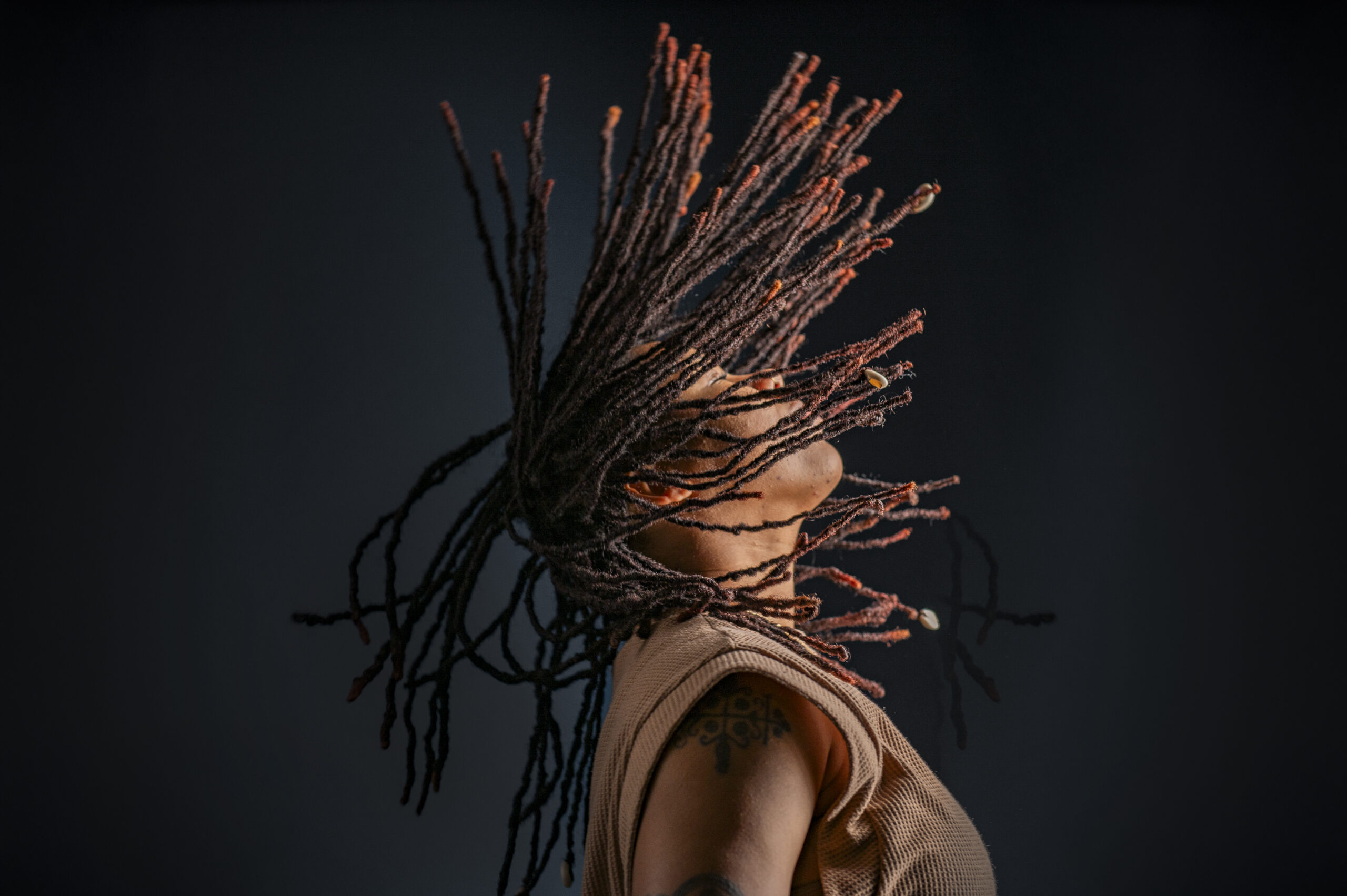 An in motion photo of Aisha, a black woman flipping her hair while gazing upwards